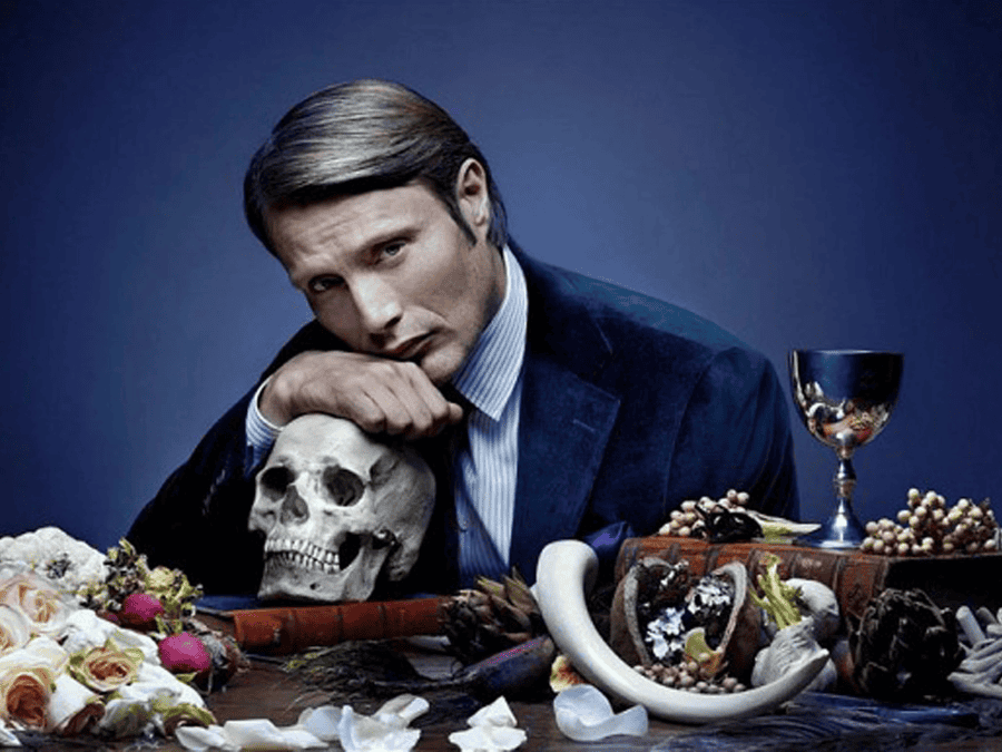 Mysterious man with skull surrounded by flowers and artifacts, dark background, dramatic tone.